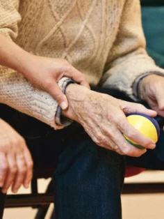 An elderly man is holding a ball.