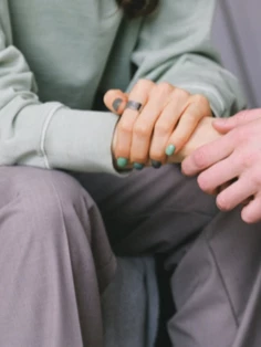 Two people are sitting on a chair, holding hands