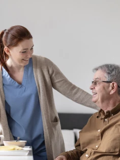 A caregiver attending to an elderly man who is currently eating